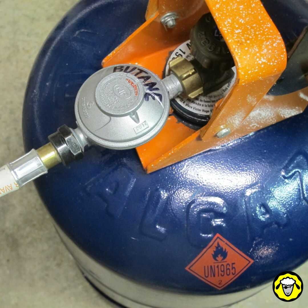 Détail du branchement d'un chauffage d'appoint au gaz sur une bouteille de butane. Il faut simplement un détendeur et un tuyau à gaz en caoutchouc.