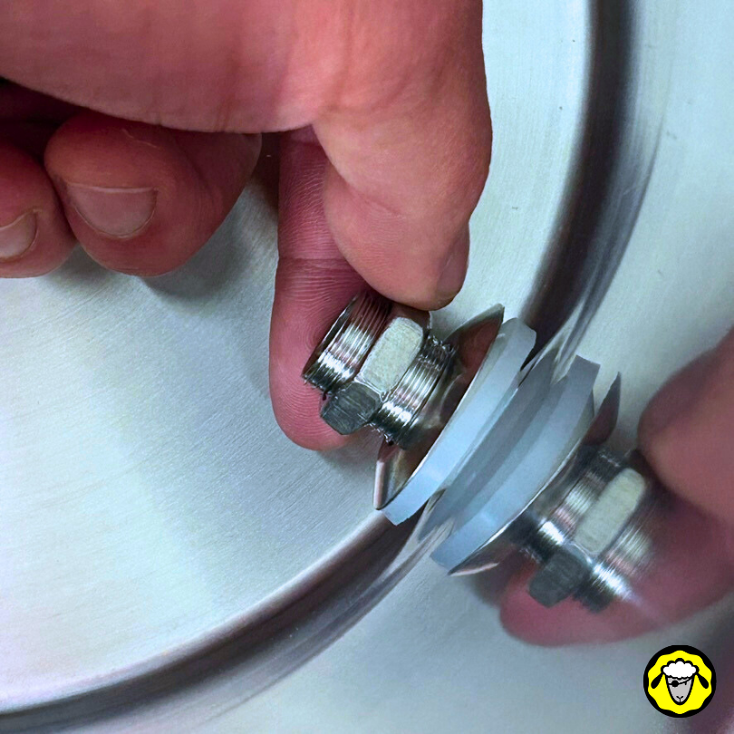 Détail de l'installation d'un écrou en inox pour le robinet d'un filtre à eau Pure Filters, focus sur la fixation, depuis l'intérieur de la cuve basse.