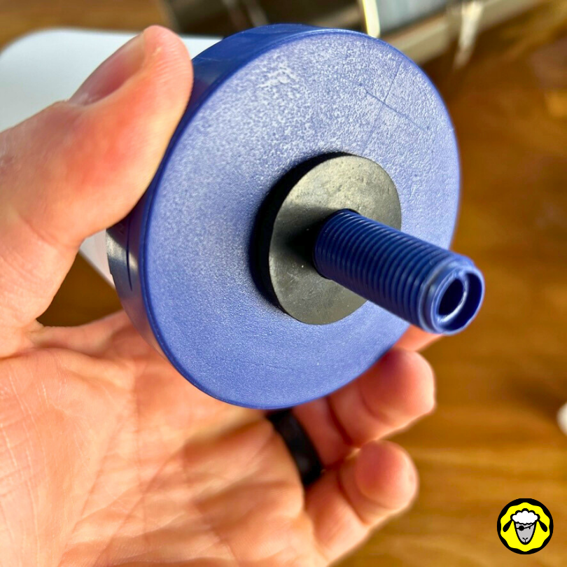 Main tenant un filtre céramique et charbon actif FTO PLUS de Coldstream pour filtre à eau a gravité. Détail de la fixation avec un filetage bleu et un joint étanche.