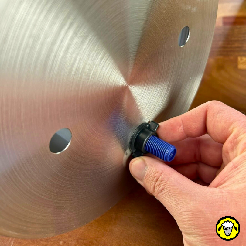 Vue de dessous de la cuve supérieure. Le filetage bleu d'un filtre à eau est attaché de manière étanche à la cuve inox via l'ecrou en plastique en noir que la main ajuste.