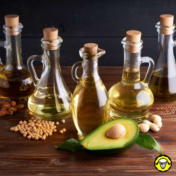 bouteilles-d-huiles-vegetales Bouteilles en verre d'huiles végétales, accompagnées d'un avocat coupé en deux et de graines variées.