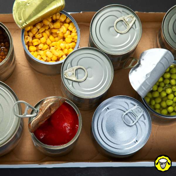 conserves-alimentaires-ouvertes Plusieurs boîtes de conserve ouvertes contenant du maïs, des petits pois, et de la sauce tomate.