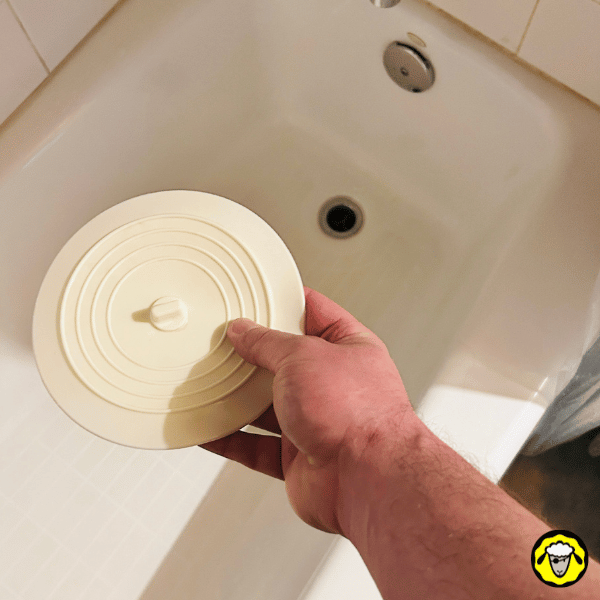 Utilisation d’un bouchon pour bloquer l’évacuation d’eau d’une baignoire, une astuce survivaliste pour stocker de l’eau en cas de besoin.