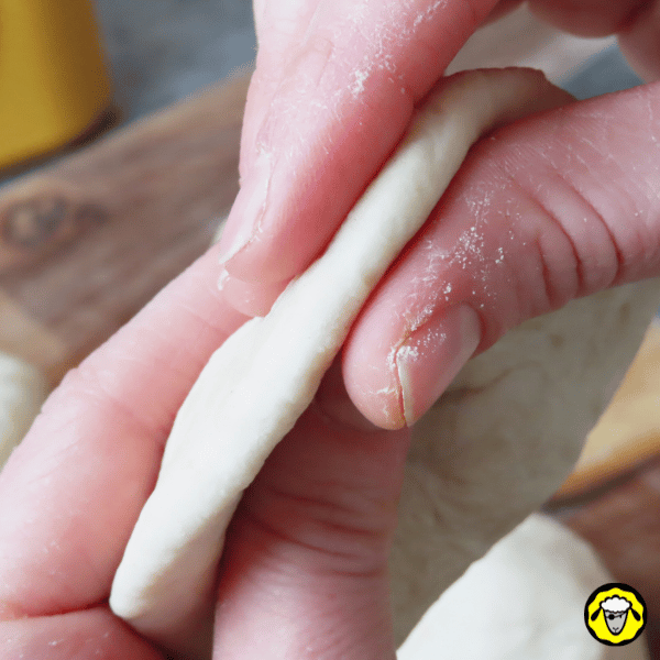 pain-maison-facile-cuit-a-la-poele-8 Un gros plan montre l’épaisseur d’un disque de pâte entre deux doigts, mettant en avant la finesse idéale pour la cuisson.