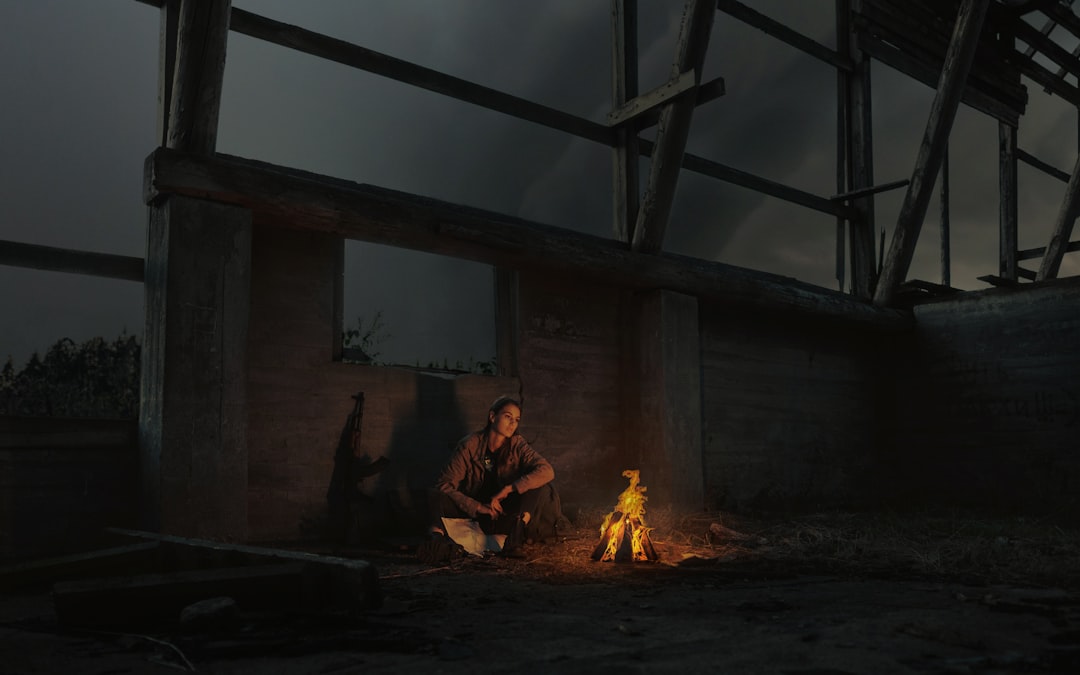 man in brown jacket sitting on chair near bonfire
