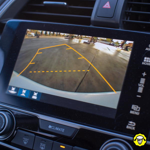 Écran de caméra de recul active affichant les repères de guidage pour stationnement assisté. Illustration d’une dépendance aux technologies modernes en matière de conduite, à opposer à l’apprentissage des compétences mécaniques essentielles pour une vie résiliente.