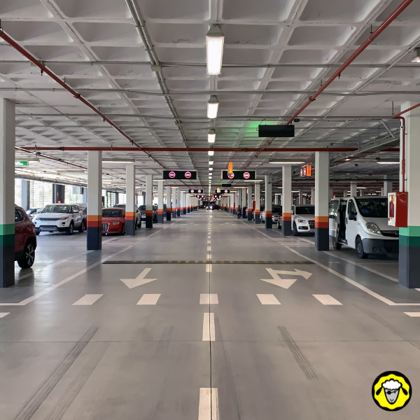 Entrée d’un parking moderne avec flèches de circulation. L’image rappelle l’importance de respecter le sens de la marche pour stationner efficacement. Une habitude de conduite qui rejoint la logique survivaliste : toujours se positionner prêt à réagir.