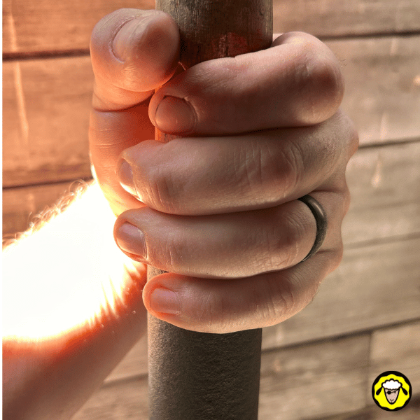 Alliance en silicone noire portée lors d’un travail manuel, main serrant un manche. Bague tactique low-profile, sécurisée et discrète, idéale pour survivalisme et activités à risque.