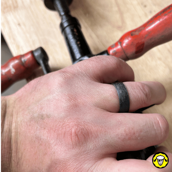 Alliance en silicone noire portée au doigt lors de l’utilisation d’un outil manuel. Bague tactique low-profile, idéale pour survivalistes, métiers manuels et activités à risque.