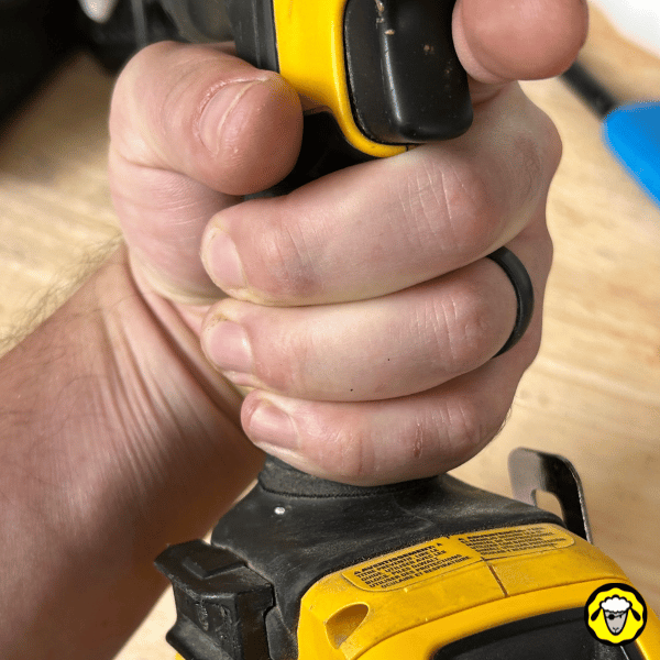 Alliance en silicone noire tactique portée lors de l’utilisation d’un outil électroportatif. Alternative sécurisée aux bagues métalliques pour survivalistes, outdoor et métiers à risque.