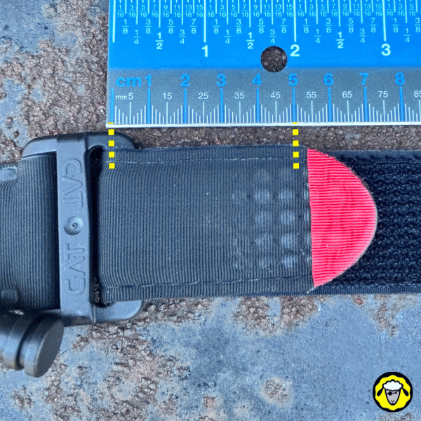 Garrot-CAT-Pliage-Tactique-Compact-1 Gros plan d’un garrot CAT Gen7 avec règle graduée en centimètres, montrant la largeur de la sangle (environ 5 cm), étape préparatoire avant pliage.