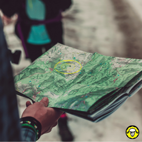 Personne tenant une carte IGN en extérieur, avec des cercles tracés en jaune pour représenter des distances, illustrant l’importance de reporter ses repères sur une carte papier.