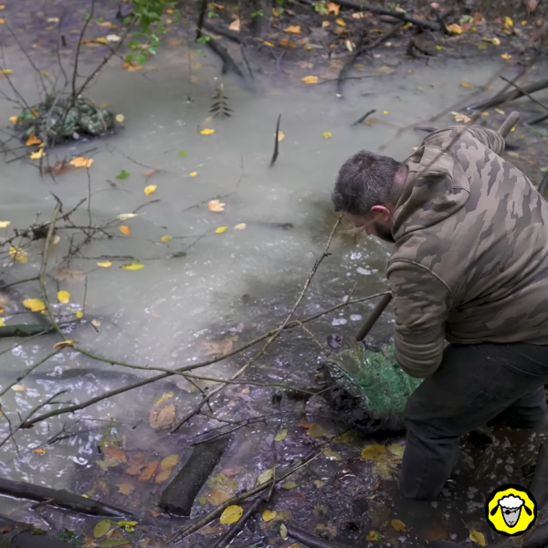 Scandale_Nestlé_Pollution_Decharge_Plastique_2 Un homme en tenue camouflage extrait une énorme masse de plastique du lit d’un ruisseau boueux. Il s’agit d’une pollution causée par une décharge sauvage de bouteilles Vittel (Nestlé) enfouies dans la nature depuis des années.