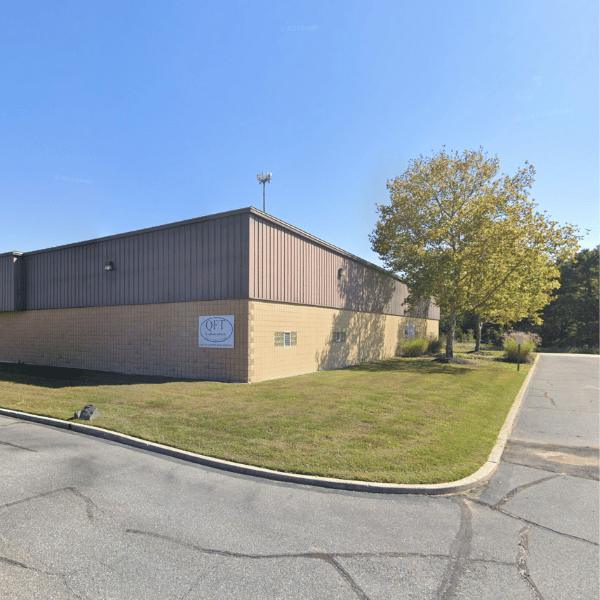 Bâtiment industriel moderne situé à Monroe Township, New Jersey (USA), avec une enseigne « QFT Laboratory » visible sur la façade. Environnement propre, route goudronnée, photo prise depuis Google Street View en octobre 2022.