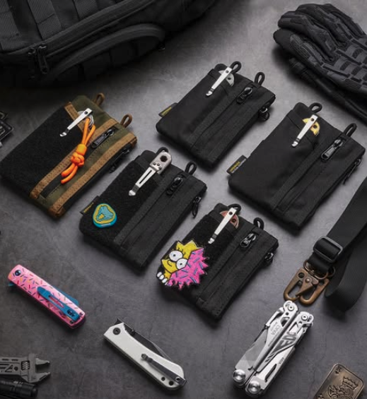 Poches EDC noires personnalisées avec patchs et outils multifonctions posés sur une surface sombre