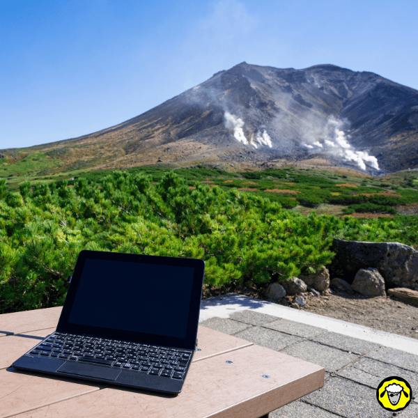 Ordinateur portable posé face à un paysage volcanique fumant, symbole du travail nomade accessible partout grâce à une connexion autonome.