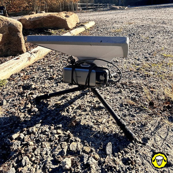 Antenne Starlink Mini posée sur un trépied Neewer et alimentée par une powerbank Anker fixée sous la base, formant une installation nomade compacte en extérieur.