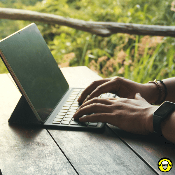 Mains tapant sur un clavier d’ordinateur en extérieur, illustrant le travail à distance en pleine nature avec une connexion fiable.