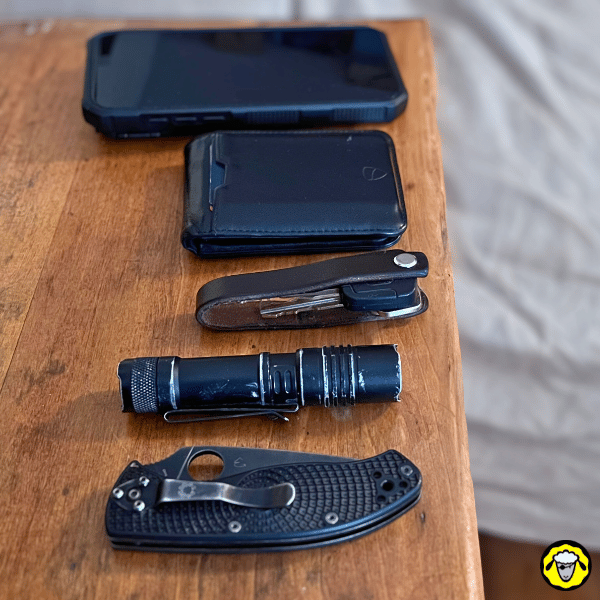 EDC à porter dans le pantalon : smartphone, portefeuille, lampe torche compacte et couteau pliant prêts à être mis en poche