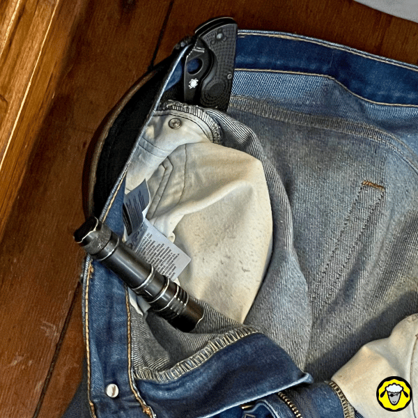 Port EDC dans le pantalon : lampe torche et couteau pliant rangés à la cveinture d’un jean, accès rapide au quotidien, et lowpro.