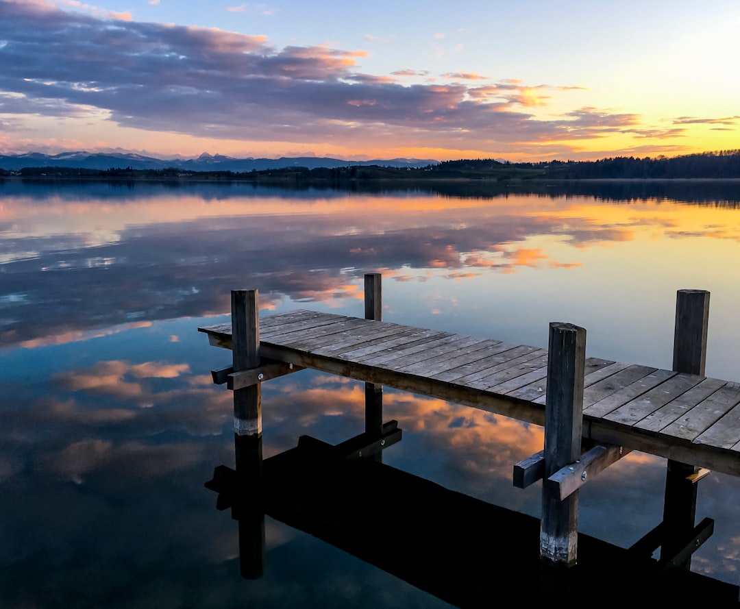Photo by Jan Huber brown wooden dock on calm water during daytime