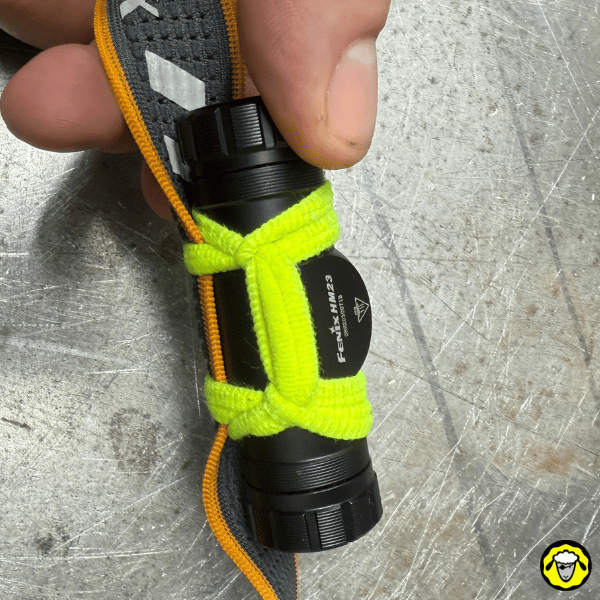 Lampe frontale Fenix HM23 fixée sur un bandeau avec un elastique a cheveux jaune pour sécuriser la lampe