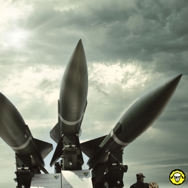 Trois missiles montes sur des lanceurs sous un ciel nuageux avec un militaire au premier plan