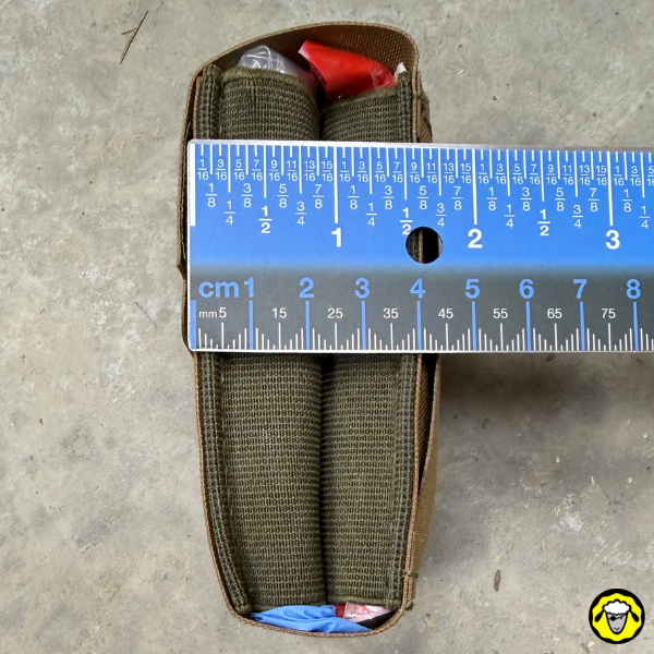 Vue latérale de la trousse Sentinel MED COMPACT remplie, mesurée avec une règle pour montrer sa faible épaisseur : 4 cm