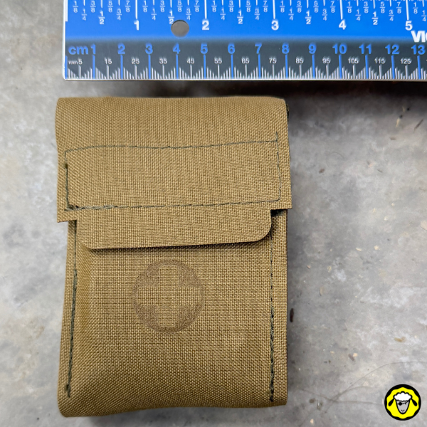 Trousse médicale Sentinel MED COMPACT fermée en Cordura, mesurée avec une règle pour montrer son format compact: 8 cm de large