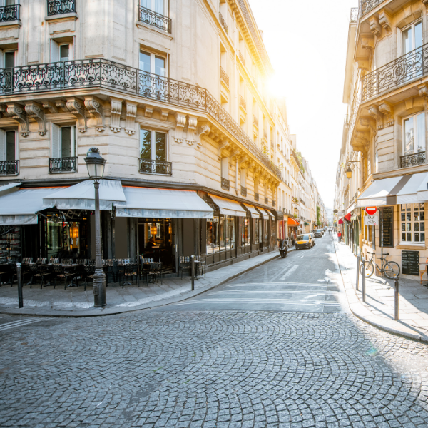 Rue pavée bordée d immeubles anciens avec terrasses de café en centre ville de Paris