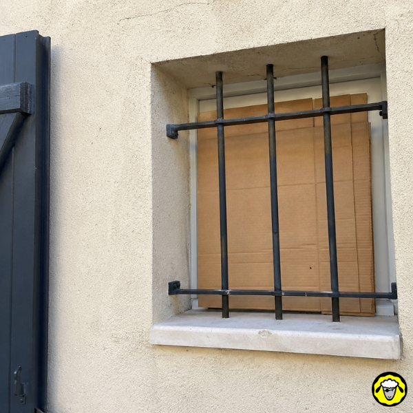 Carton placé derrière une fenêtre à barreaux pour protéger l intérieur du soleil