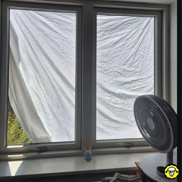 Drap blanc tendu devant une fenêtre pour limiter la chaleur et la lumière