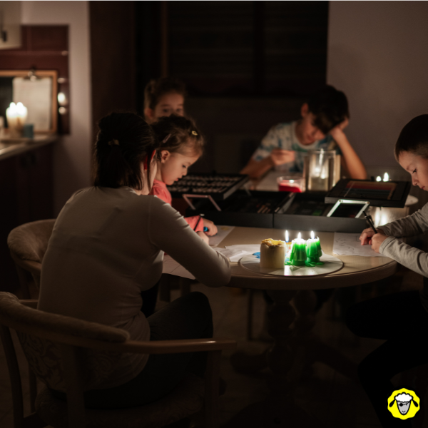 Famille réunie autour d’une table éclairée à la bougie pendant une coupure d’électricité à la maison.
