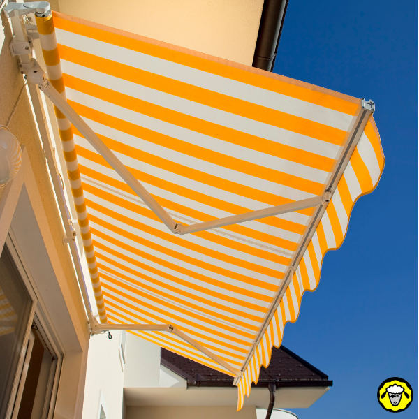 Store banne rayé jaune et blanc déployé au-dessus d une terrasse sous un ciel bleu