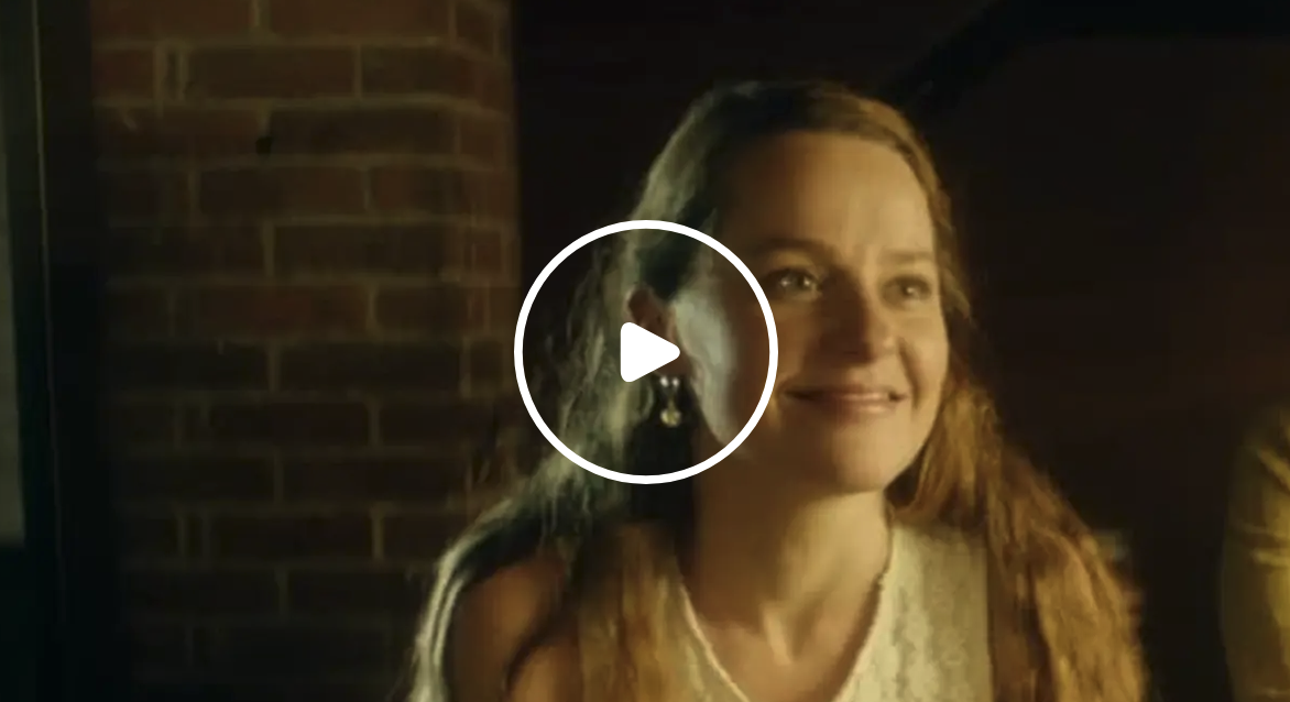 Megantic-Episode-2 Extrait de l’épisode 2 de la série Mégantic à regarder gratuitement sur Tubi : une femme sourit dans une pièce éclairée par une lumière chaleureuse.