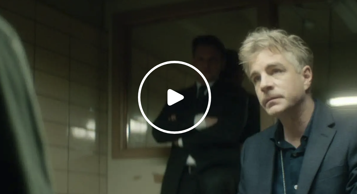 Megantic-Episode-7 Extrait de l’épisode 7 de la série Mégantic, disponible gratuitement en streaming sur Tubi : un homme aux cheveux gris est interrogé dans une pièce sombre.